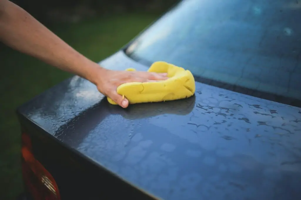 A hand wiping a car with a cloth